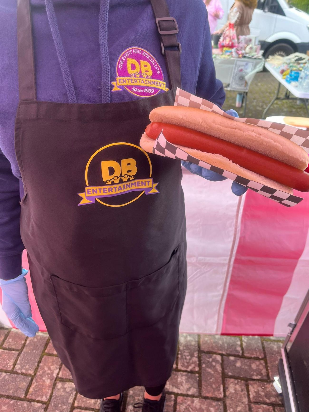 Uniformed server handing over a hot dog wrapped in a checkered paper food liner