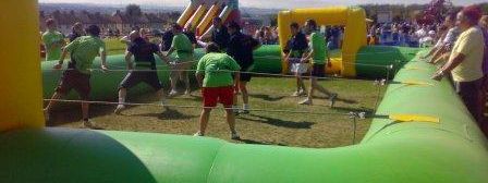 Players gripping the bars inside a giant inflatable human table football pitch