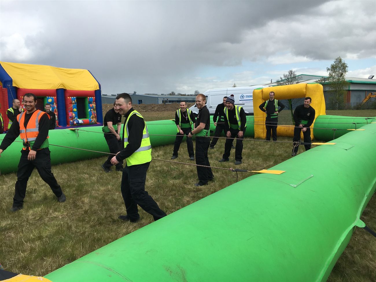 Two teams playing human table football in an inflatable arena at a corporate fun day