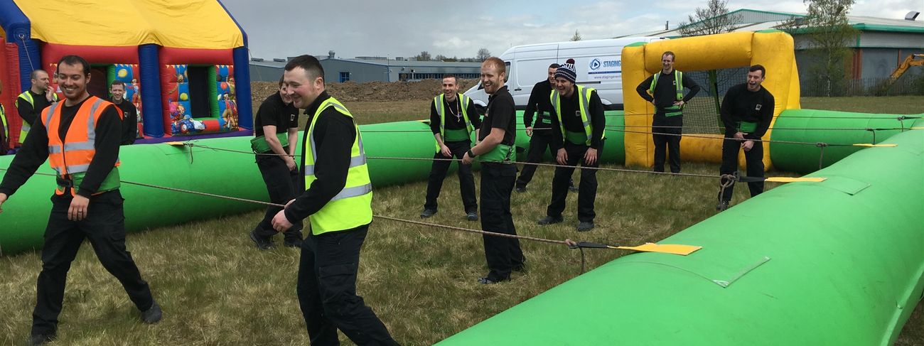 Two teams coordinating inside a giant inflatable Human Table Football arena