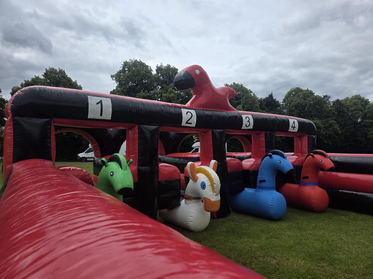 Close-up of the green, white, blue and red inflatable hopper horses in the numbered starting pens of the Grand National track