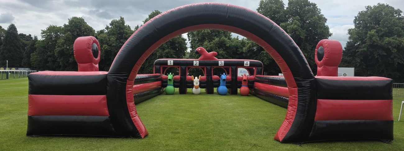 Giant red and black inflatable Grand National race track with four numbered starting pens, hopper horses ready to race and a large inflatable arch at the far end