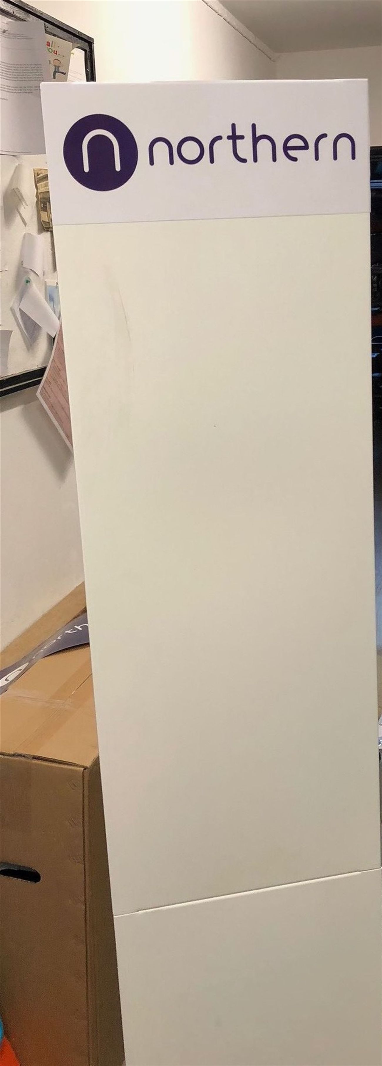 Tall white branded board with the Northern logo at the top in a storage area