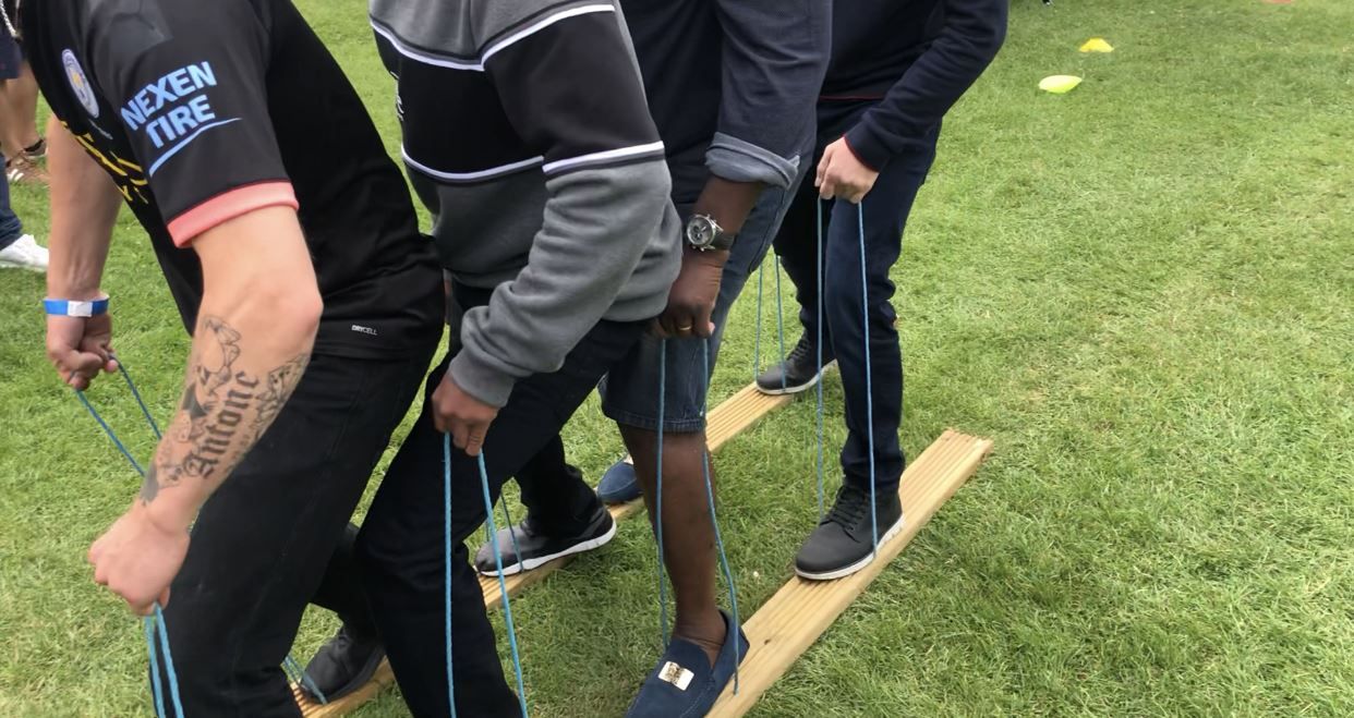 Close view of players holding blue ropes at individual positions on wooden team skis