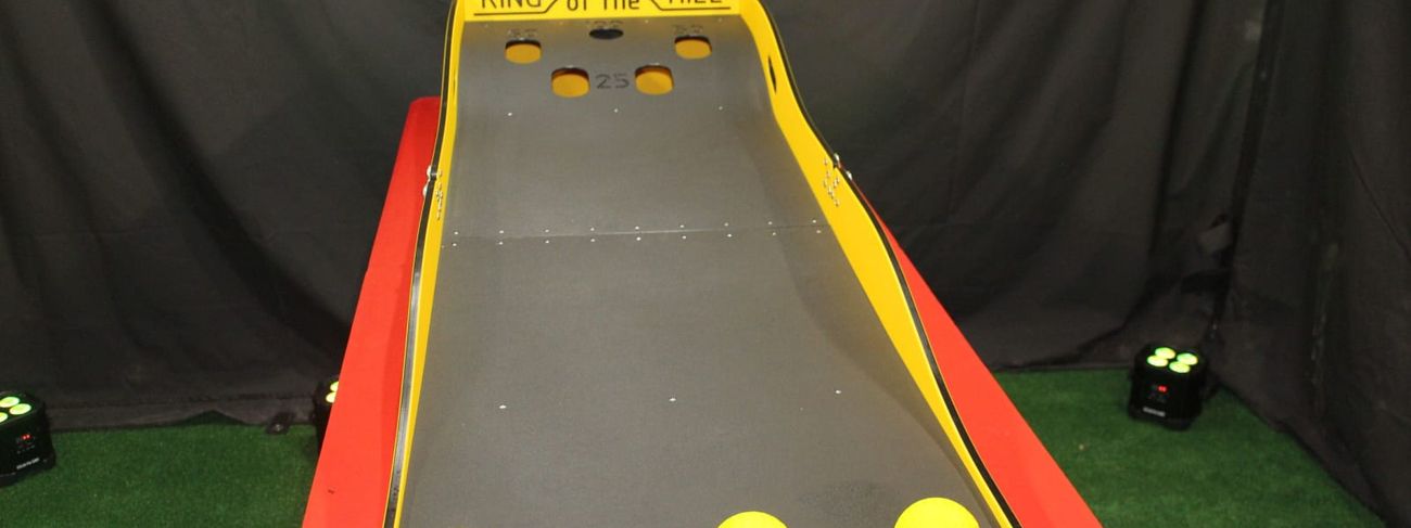 King of the Hill - yellow tabletop ramp game with three yellow balls at the player end and five scoring holes at the top