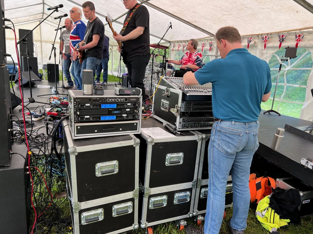 Sound engineer operating a flight-cased mixing desk for a live band