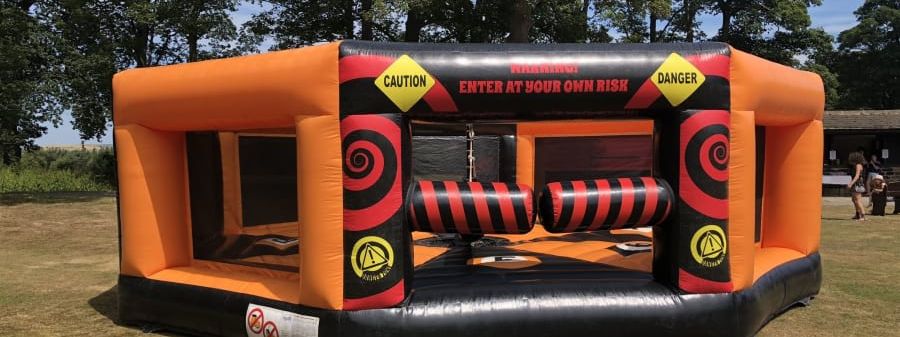 Last One Standing with Walls Wipeout, a blue and black walled inflatable sweeper arena with padded entrance pillars