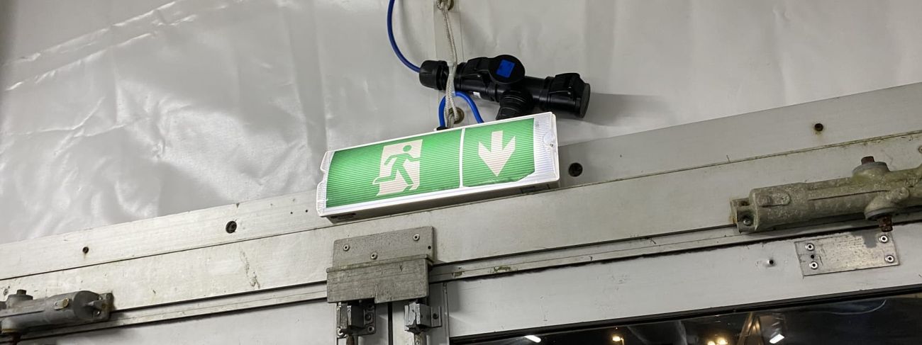 Green LED emergency exit sign mounted above a sliding door inside a marquee