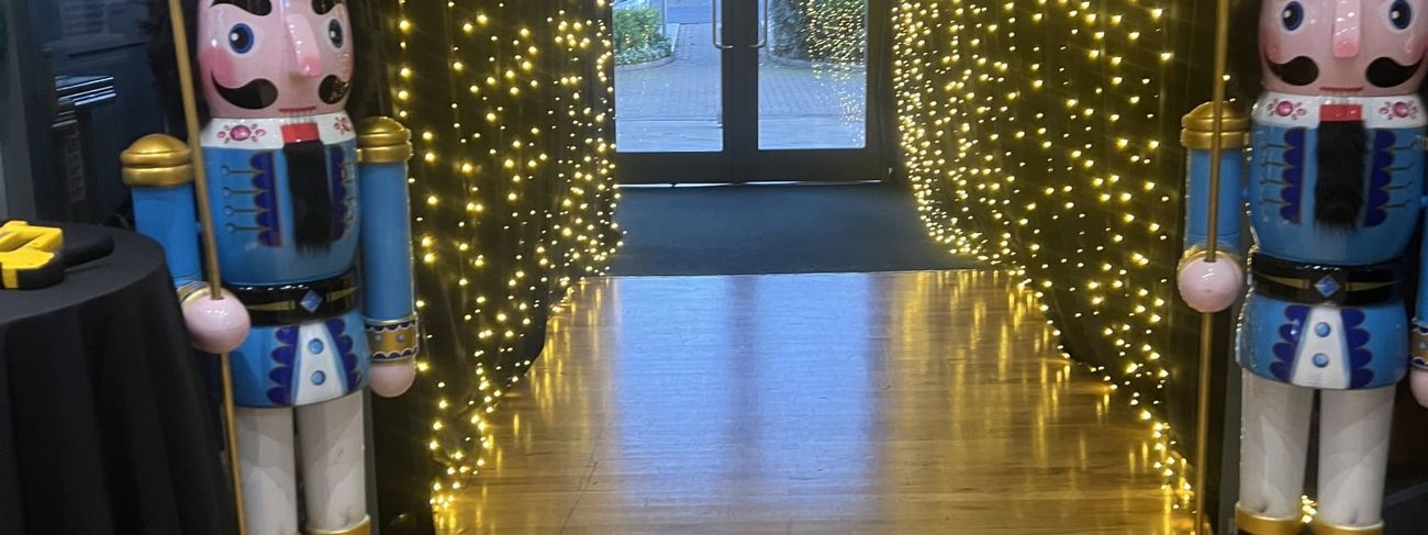 Pair of giant nutcracker props flanking a fairy-light entrance archway