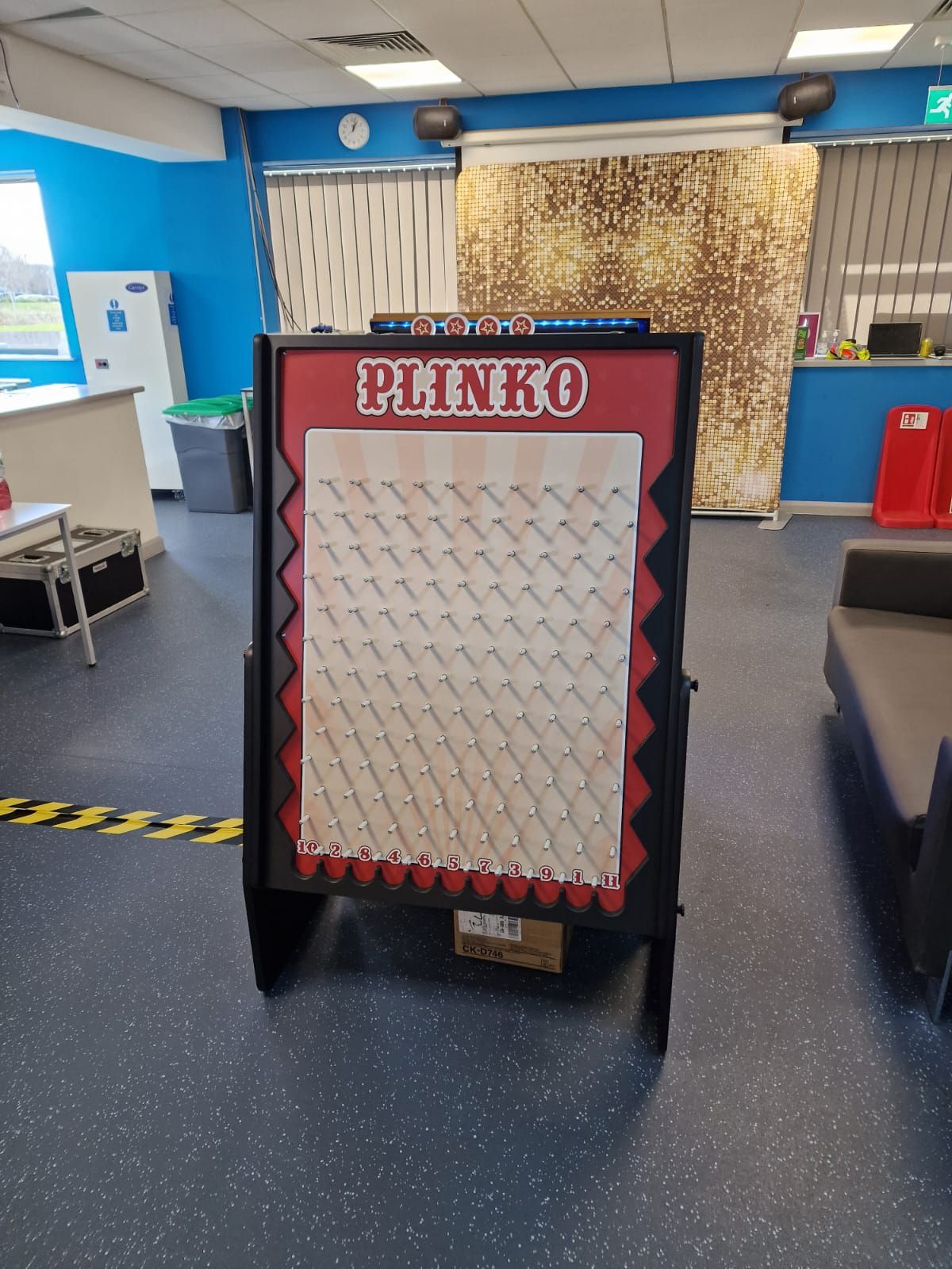 Plinko peg board with light-up top sign in a hire warehouse