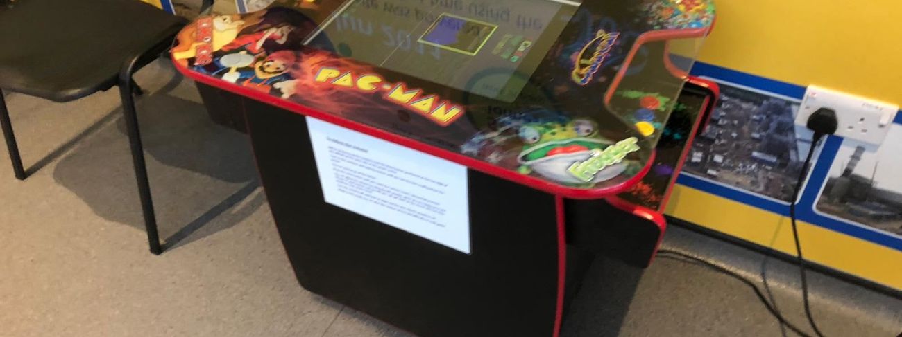 Retro cocktail arcade table set up indoors for guests to sit and play
