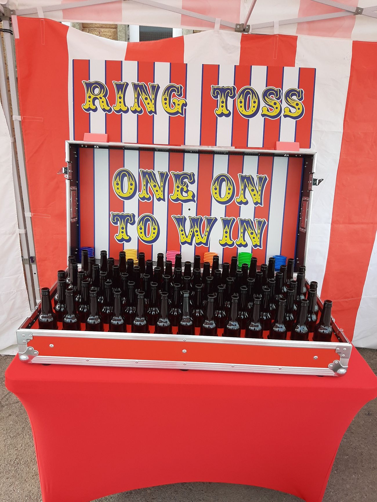 Rows of dark glass bottle targets with coloured throwing rings stacked behind them in the Ring Toss flight case