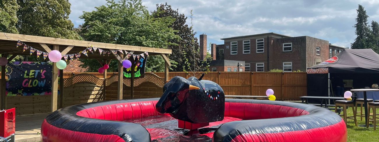 Black mechanical rodeo bull in a red-and-black inflatable safety bed