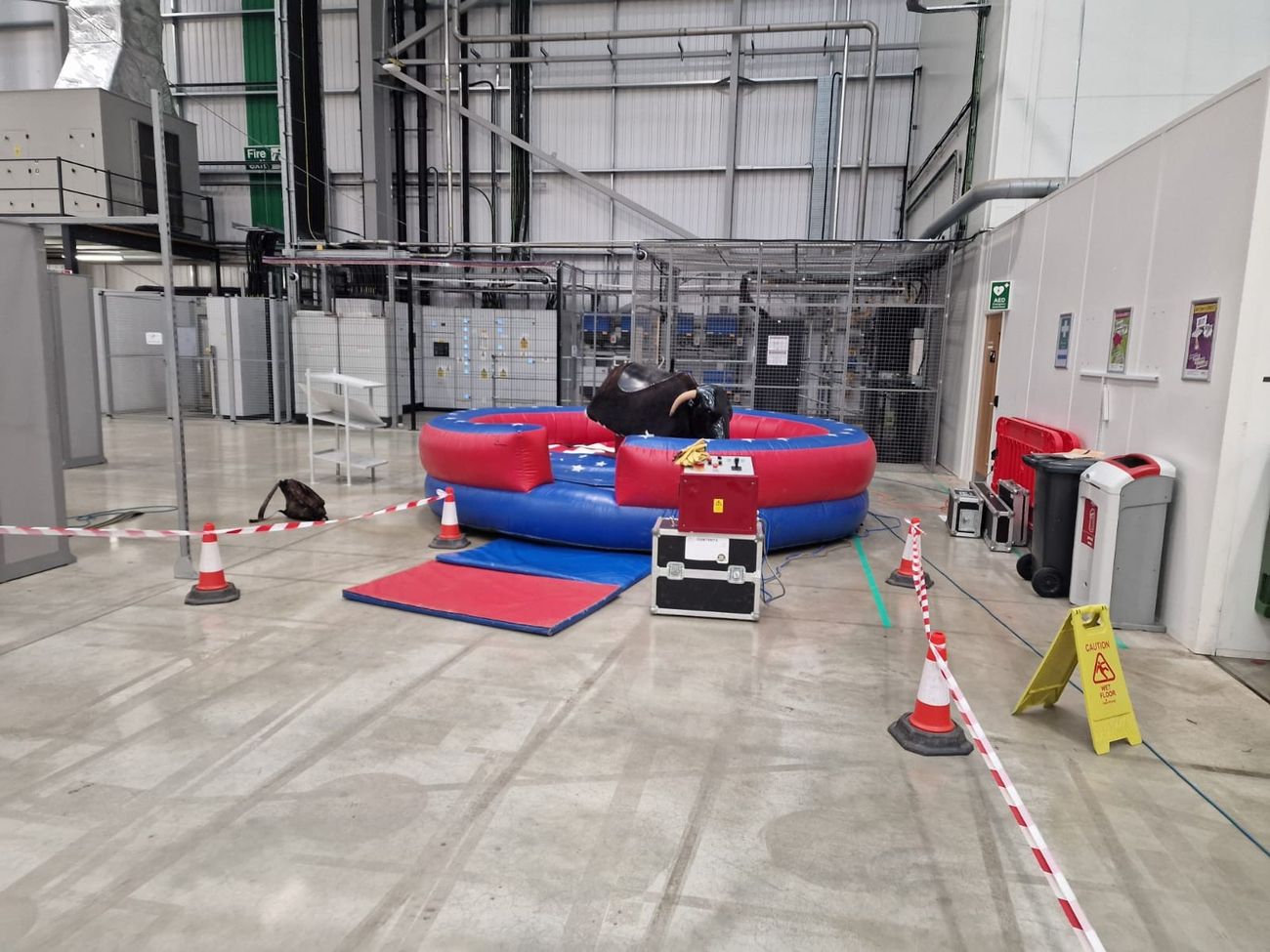 Mechanical rodeo bull with inflatable bed, control console and entrance mats set up indoors