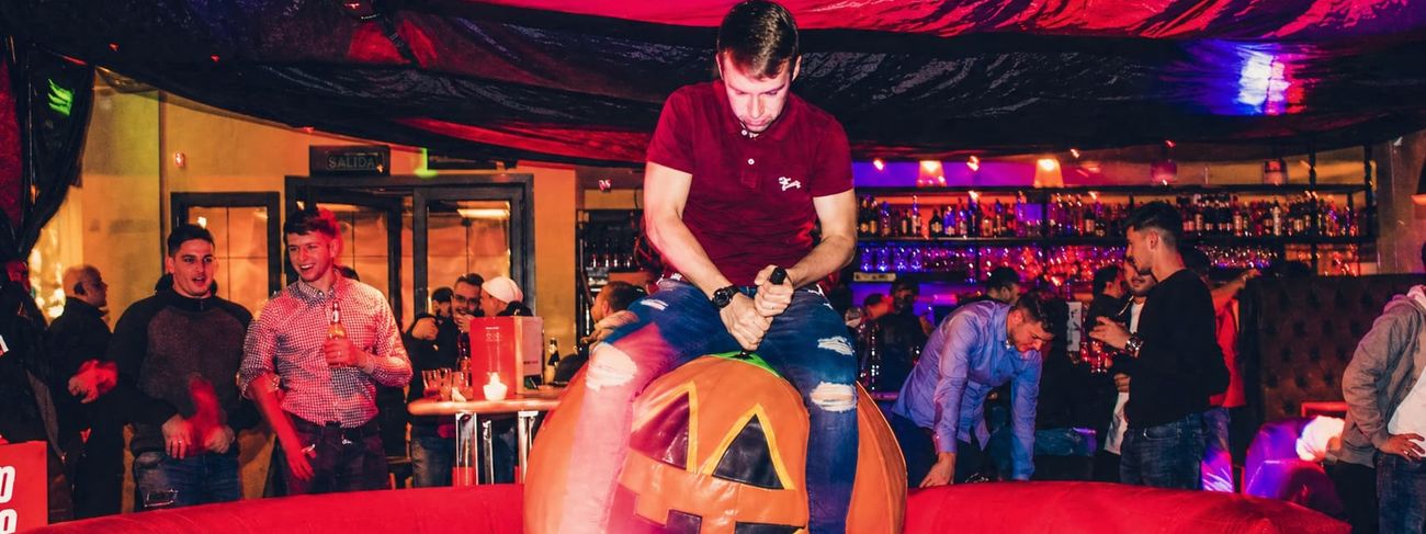 Halloween rodeo pumpkin inflatable in use at a bar event under red ceiling drape