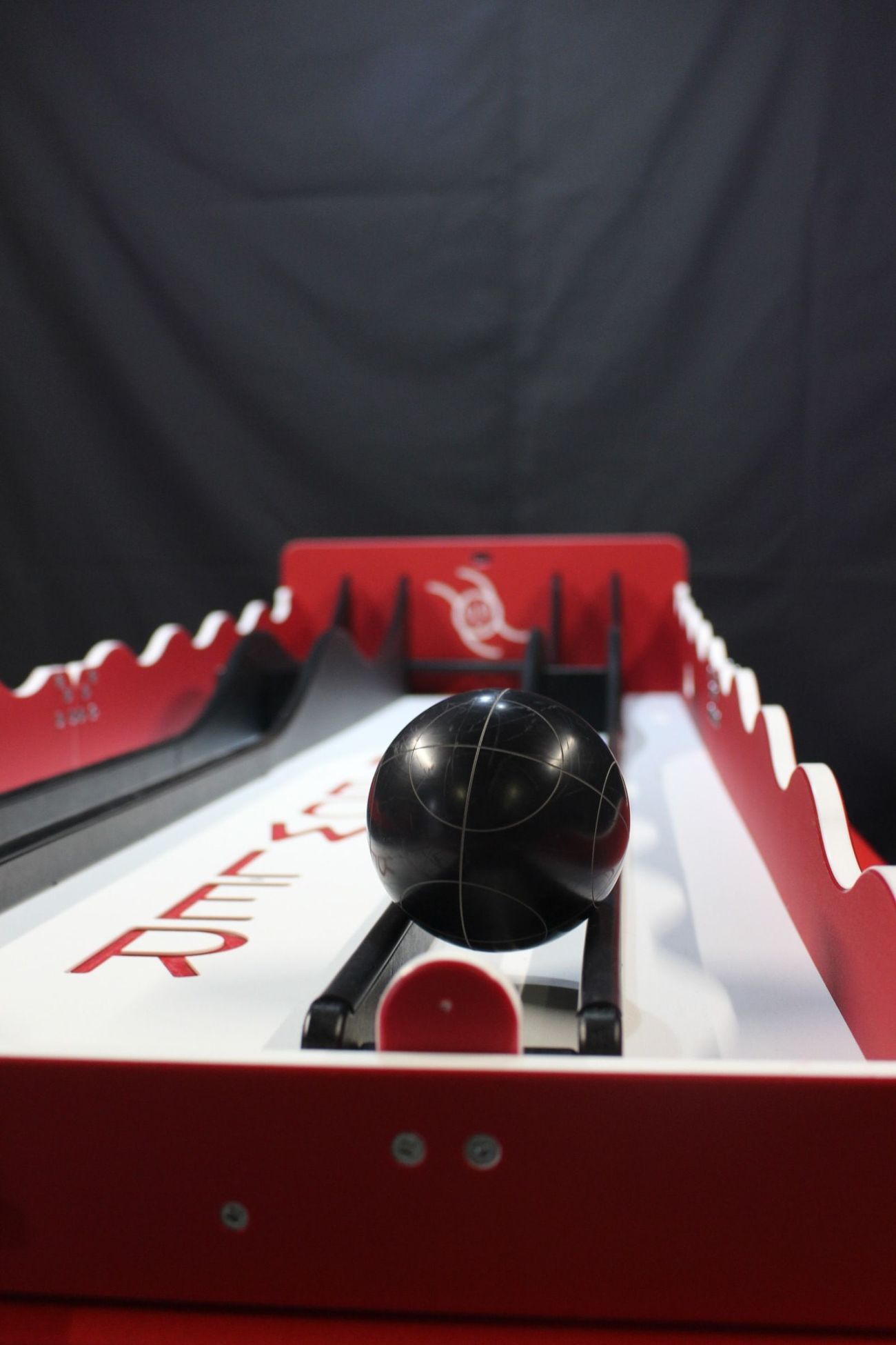Close-up of a black bowling ball balanced on the Roller Bowler track ramp