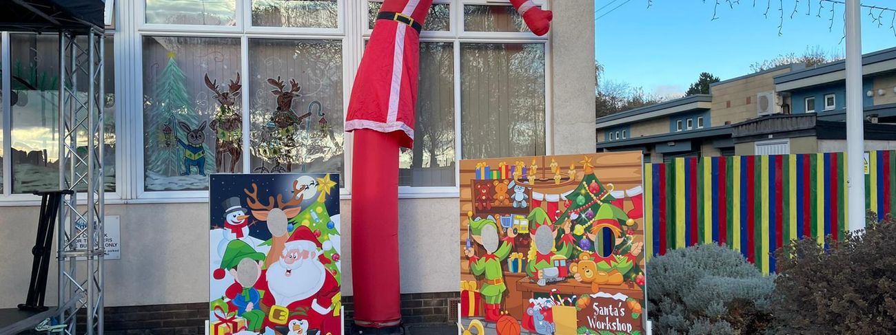 20ft inflatable Father Christmas sky dancer waving beside Christmas selfie boards at a school event