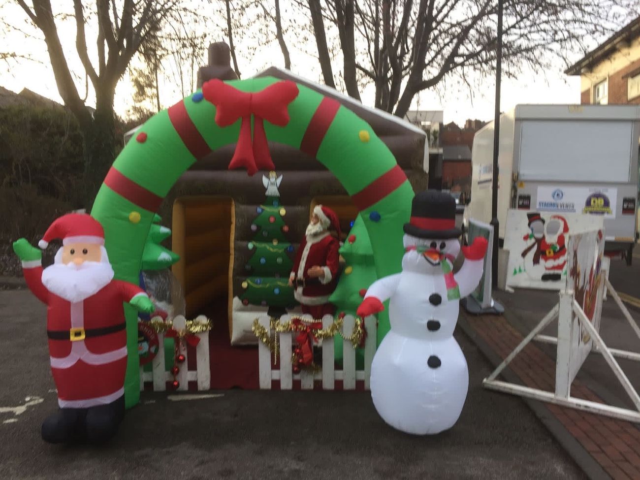 Front view of the inflatable grotto with waving Santa, snowman and wreath arch over the entrance