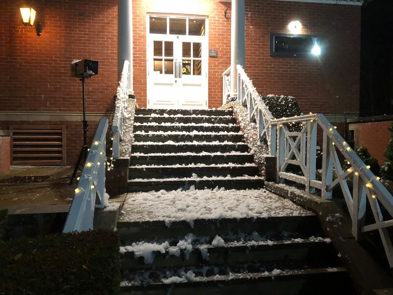 Snow-covered entrance steps with festive lights