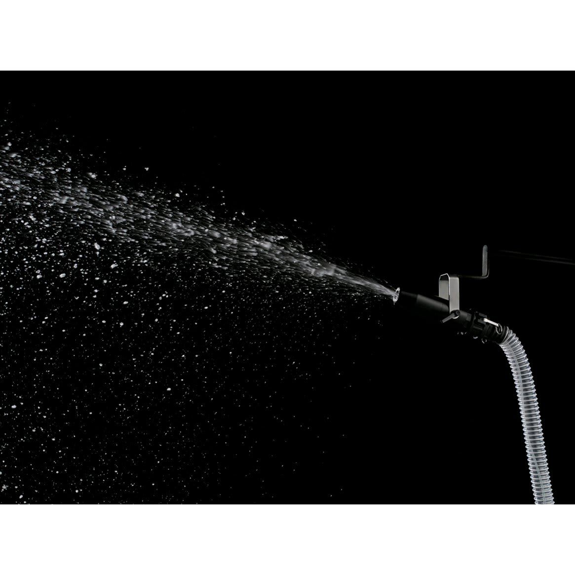 Snow spraying from the rigging nozzle in a wide fan against a dark background