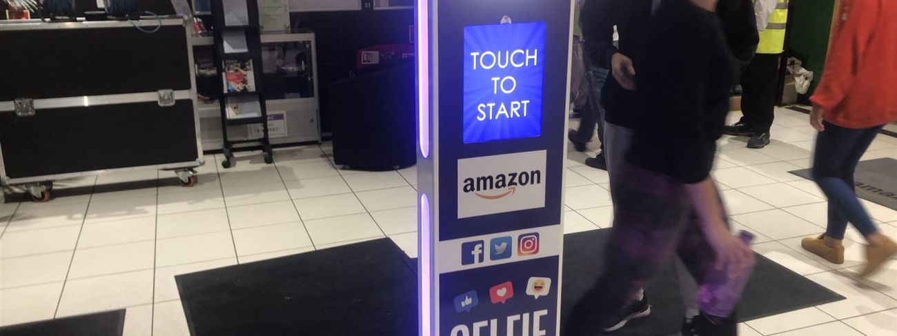 Selfie pod at an Amazon fulfilment centre entrance with staff walking past