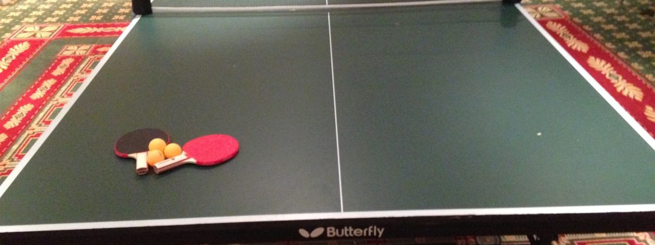 Butterfly-branded table tennis table with two paddles and orange balls set up in a function room