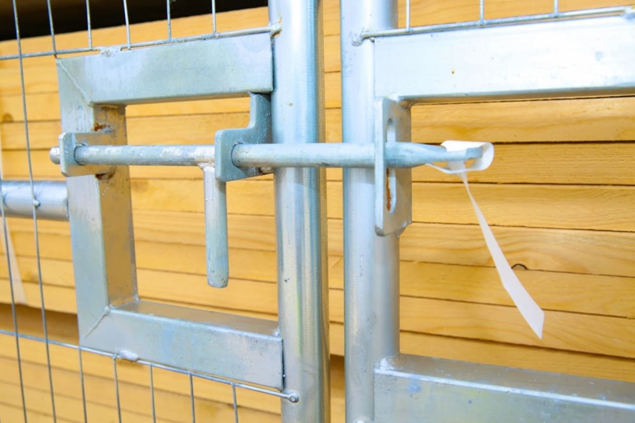 Close-up of the galvanised drop-bolt latch joining two temporary fence gate panels