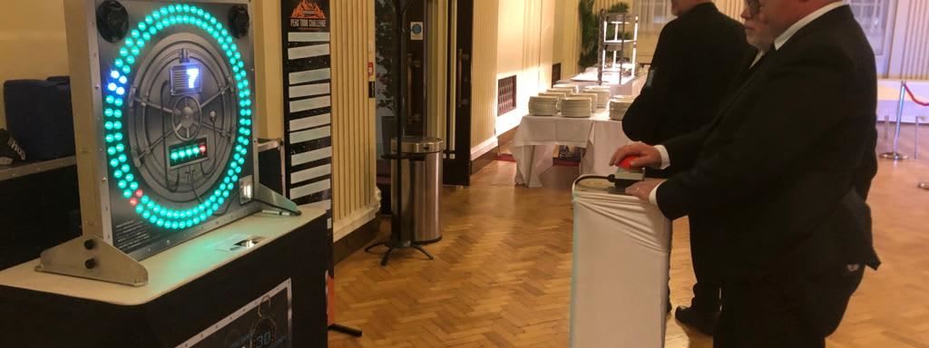 Two guests in black tie pressing the trigger at a plinth-mounted Vault at a formal event