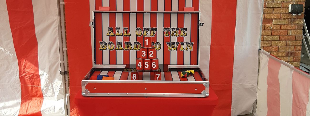 Tin Can Alley flight-case stall with eight numbered cans stacked in a pyramid, ready for players to throw