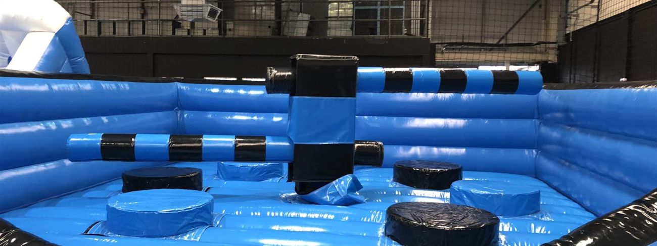 Ultimate Wipeout inflatable sweeper arena, twin arms extended, indoor warehouse setup