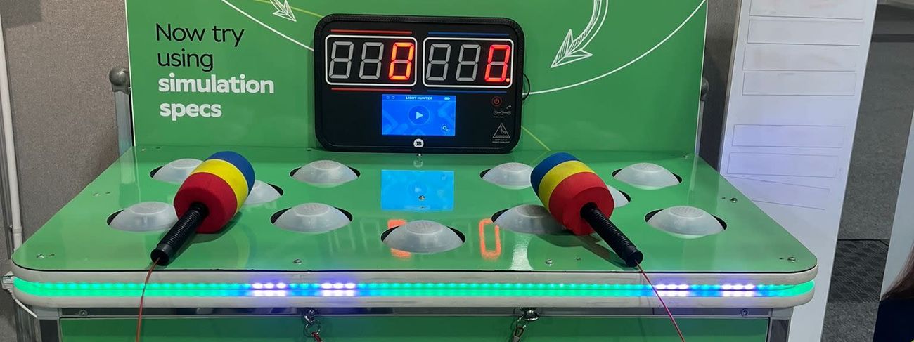 Specsavers-branded Whack a Mole on an exhibition stand with a "test your vision and reaction" header and a leader board sign